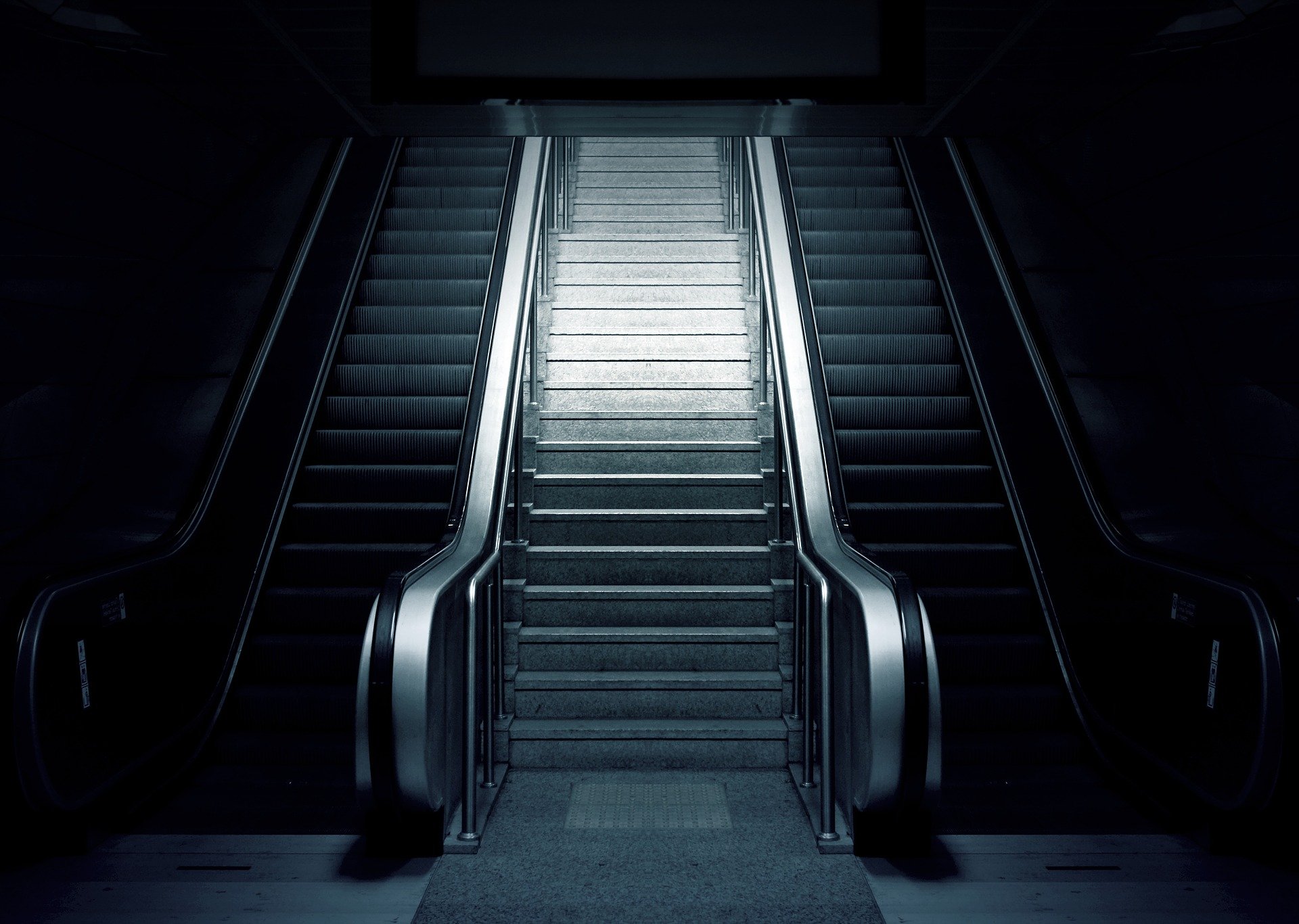 Schwarz-weiß-Foto einer Treppe zwischen zwei Rolltreppen.
