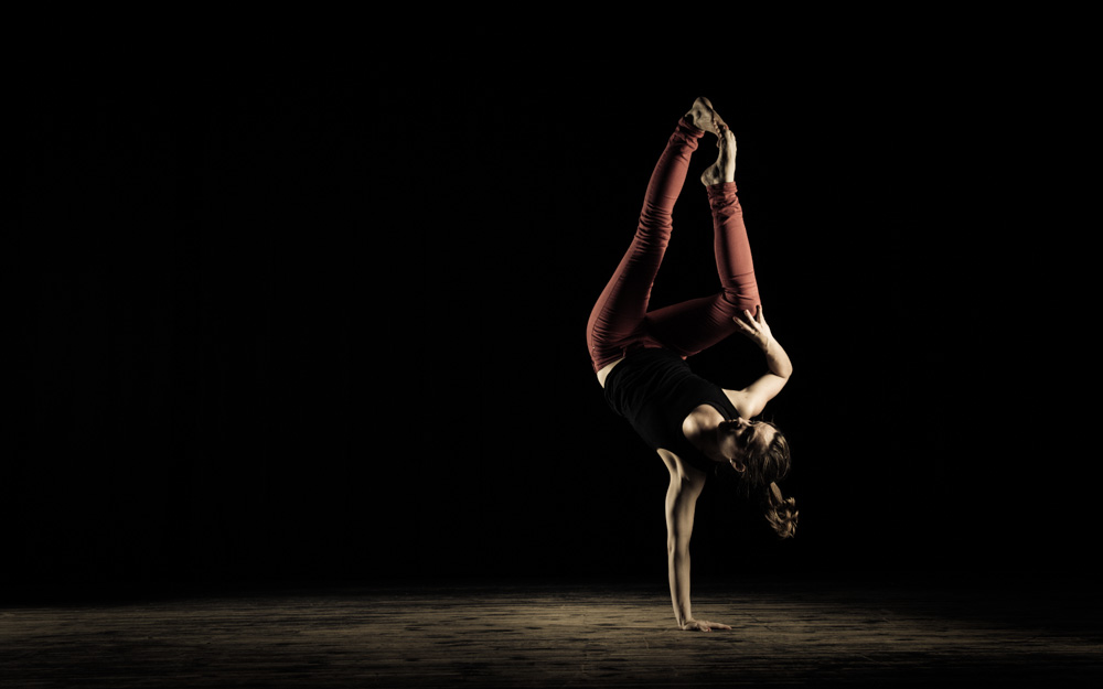 Pia-Verena Grohmann in einer akrobatischen Figur auf einer Hand stehen.